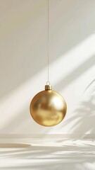 A minimalist Christmas poster featuring a single golden bauble on a beige surface with a strong, natural shadow play.