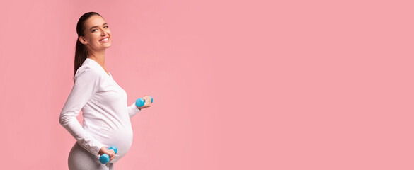 Pregnancy Fitness. Pregnant Girl Exercising With Dumbbells Smiling Standing Over Pink Studio...