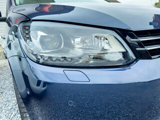 Close-up view of a sleek blue car's headlight capturing the essence of modern automotive design in a clean, bright outdoor setting