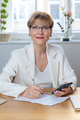 Portrait of business woman. Confident mature woman using mobile phone and typing. Vertical photo. High quality photo