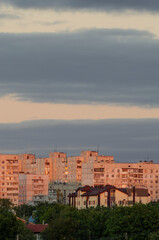 Fototapeta premium Здания на закате освещенные закатным солнцем, тучи