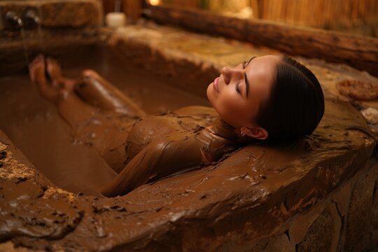 Woman enjoys a relaxing mud bath at a spa environment.