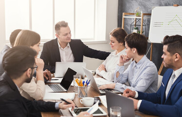 Business meeting of young team. Cheerful people brainstorming, discussing successful contract and great profit in office, copy space