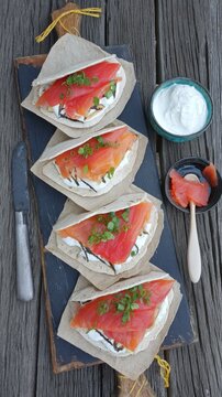 Delicious norwegian rakfisk served on flatbread with fresh sour cream and onions on a rustic wooden table