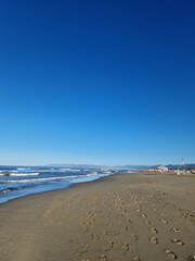 Human footprints in the sand on the coast of Forte de Marmi, Italy. Shot on a phone camera.