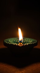 A lit diya lamp with a bright flame against a dark background, symbolizing light and hope during festivals like diwali