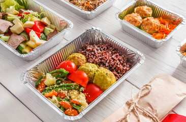 Healthy restaurant food. Chef prepared diet daily meals delivery. Fitness nutrition, vegetables, meat and fruits in foil boxes, cutlery in craft package on wood