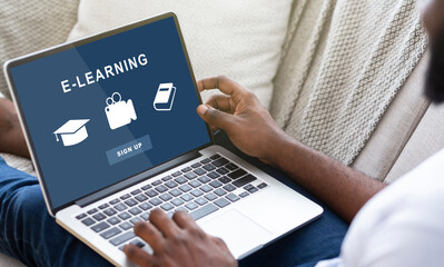 E-Learning Concept. Over the shoulder view of black man using laptop with educational website, ready to sign up for digital classroom and to watch webinar. Online education, study and stay at home