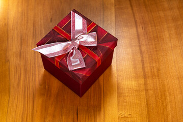 Elegant Gift Box with Red Wrapping Ribbon on a Wooden Table
