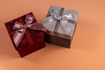 Two Elegant Gift Boxes with Ribbons on a Beige Background