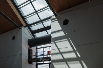 Abstract architectural interior of a modern building with concrete walls and dramatic shadows from a skylight.
