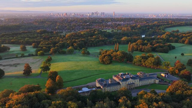 Aerial video of a golden sunrise over Heaton Park fields, woodland, and Manchester city skyline in the distance.