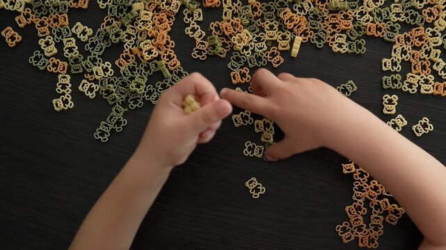 A child plays and sorts pasta in the shape of bears