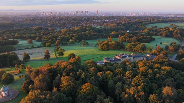 Aerial video of a golden sunrise over Heaton Park fields, woodland, and Manchester city skyline in the distance.