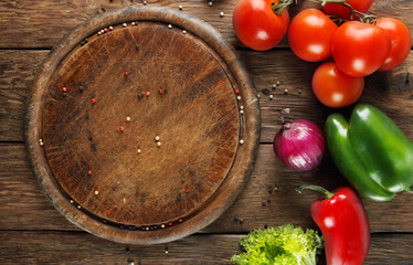 Various vegetables at wooden rustic background with copyspace on round pizza desk. Set of fresh vegetables. Vegetables top view, tomatoes, pepper, lettuce, onion, garlic, red onion. Pizza ingridients.