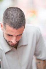 Obraz premium A man with a shaved head is looking at the camera. He is wearing a white shirt and has a tattoo on his arm