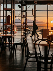 A stunning sunset view from a cafe featuring a person walking in silhouette. Perfect for travel themes.