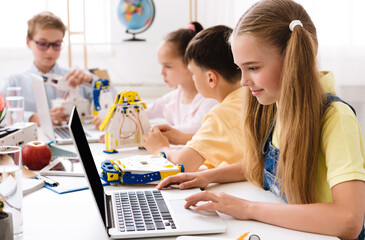 Fototapeta premium Stem education. Girl programming diy robot with laptop, studying modern technologies