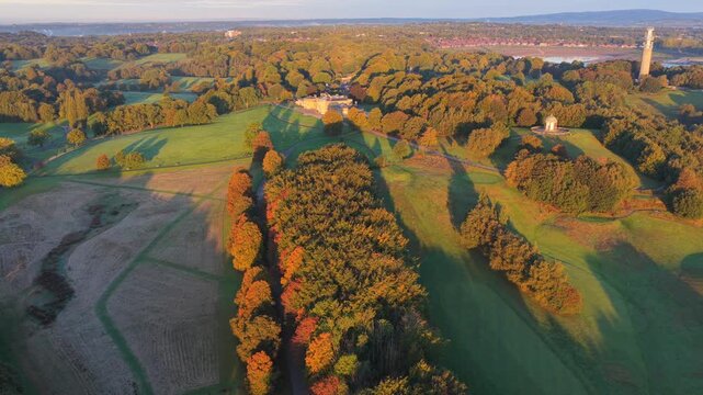 Sunrise aerial video of Heaton Park in Prestwich, Manchester with lush fields, trees, and the temple surrounded by morning light.