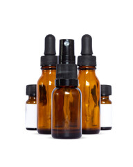 Group of five amber glass bottles for skincare and beauty products, featuring droppers, spray mist, and blank white labels. Ideal packaging mock-up for brand presentation and essential oils.