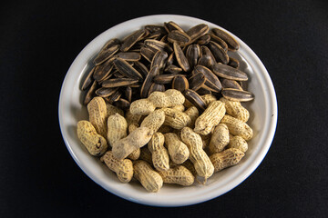 Photograph, Top view of mixed salted peanuts and kuaci (sunflower seeds) served in a plate for snack concept.