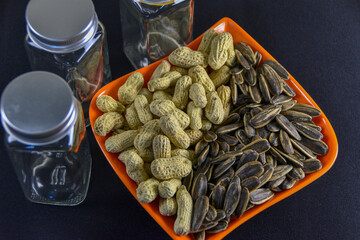 Photograph, Top view of mixed salted peanuts and kuaci (sunflower seeds) served in a plate for snack concept.