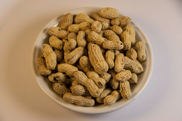 Photograph, one plate of salt peanuts is on a white table