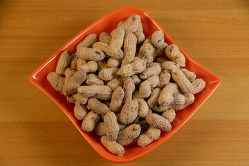 Photograph, one plate of salt peanuts is on a light brown table