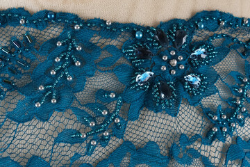 Textured and patterned background. Blue brocade. Floral embroidery adorned with pearl beads.
