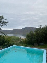 Blue pool by ocean in Westfjords Iceland with mountain view