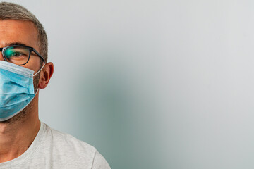 Man wearing a mask while looking to the side in a neutral setting