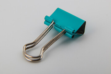 Colorful binder clip resting on a plain background in a workspace setting