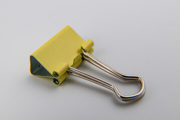 Yellow binder clip resting on white background for office use and organization