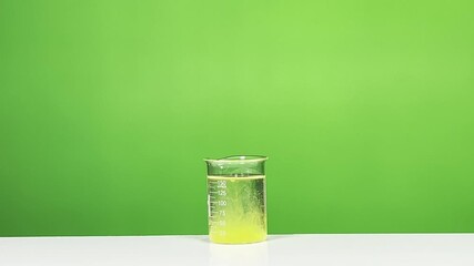 Yellow Chemical Solution Dispersing Inside Laboratory Beaker with Green Background – Science Experiment and Chemistry Concept - Powered by Adobe