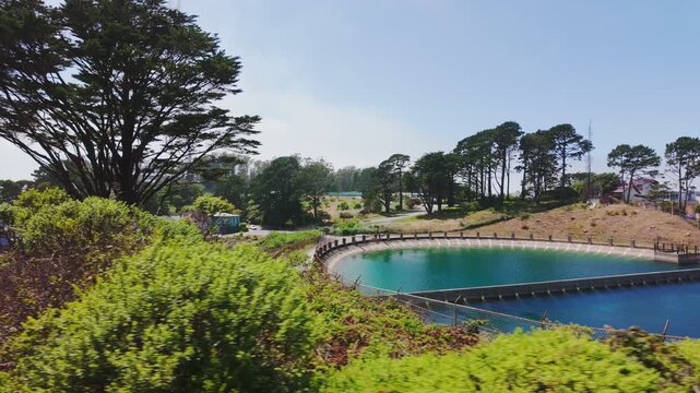 Twin Peaks Reservoir with turquoise water and Sutro Tower rising above trees in San Francisco, California, USA. Scenic urban landmark with greenery, hills and clear summer sky