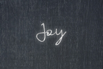 A blackboard with a handwritten chalk message that says joy, a powerful symbol of business success and motivation in educational and production concepts.