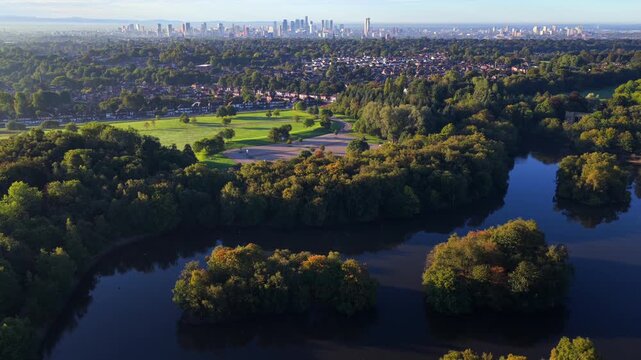 Aerial video of Heaton Park boating lake in Prestwich with Manchester skyline in the distance at sunrise.