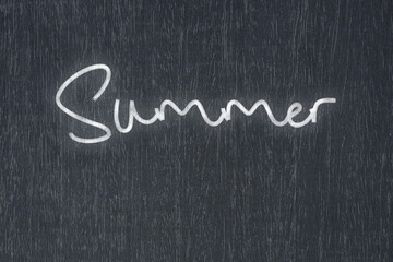 A blackboard with a handwritten chalk message that says summer, a powerful symbol of business success and motivation in educational and production concepts.