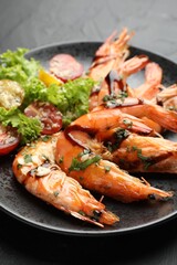 Tasty grilled shrimps served with salad on black table, closeup. Delicious seafood dish