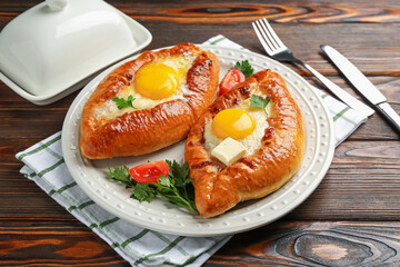 Tasty khachapuri with cheese and eggs served on wooden table