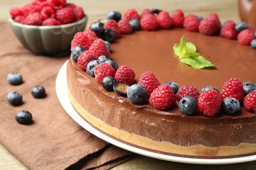 Delicious chocolate cheesecake with berries and mint on table, closeup