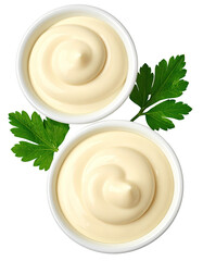 Two small white bowls filled with creamy mayonnaise, topped with swirls, nestled amongst fresh parsley leaves