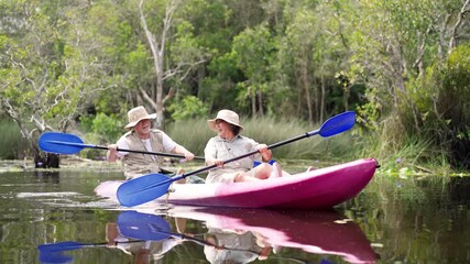 Happy Asian senior couple kayaking in the river on summer holiday vacation. Healthy retired elderly people enjoy and fun outdoor active lifestyle travel nature, sport and rowing a boat in the lake. - Powered by Adobe