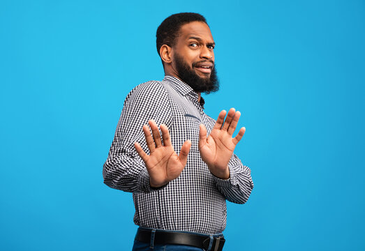 Ew, It's So Gross. Young african man with disgusted expression repulsing something, saying please stop, blue wall