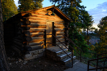 Evening sunlight highlighting classic park service log cabin in ponderosa pine forest, north rim Grand Canyon National Park, Arizona
