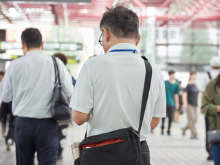 夏の朝の通勤時間の名古屋の金山駅の構内にいる中年男性サラリーマンの姿