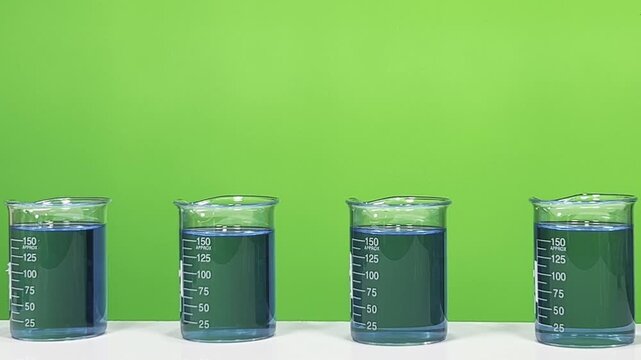 Row of Laboratory Beakers Filled with Blue Chemical Solution in Front of Green Background &ndash; Scientific Experiment Setup
