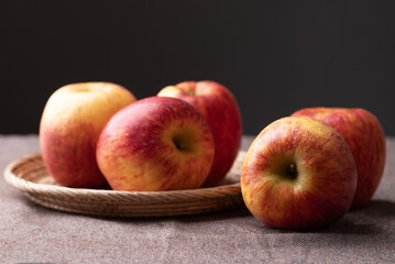 Red apple fruit (Envy apple) in basket on brown fabric with black background