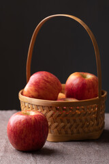 Red apple fruit (Envy apple) in basket on brown fabric with black background