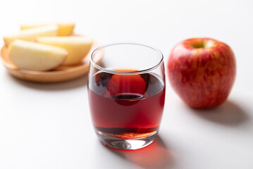 Glass of apple cider with red apple fruit on white background